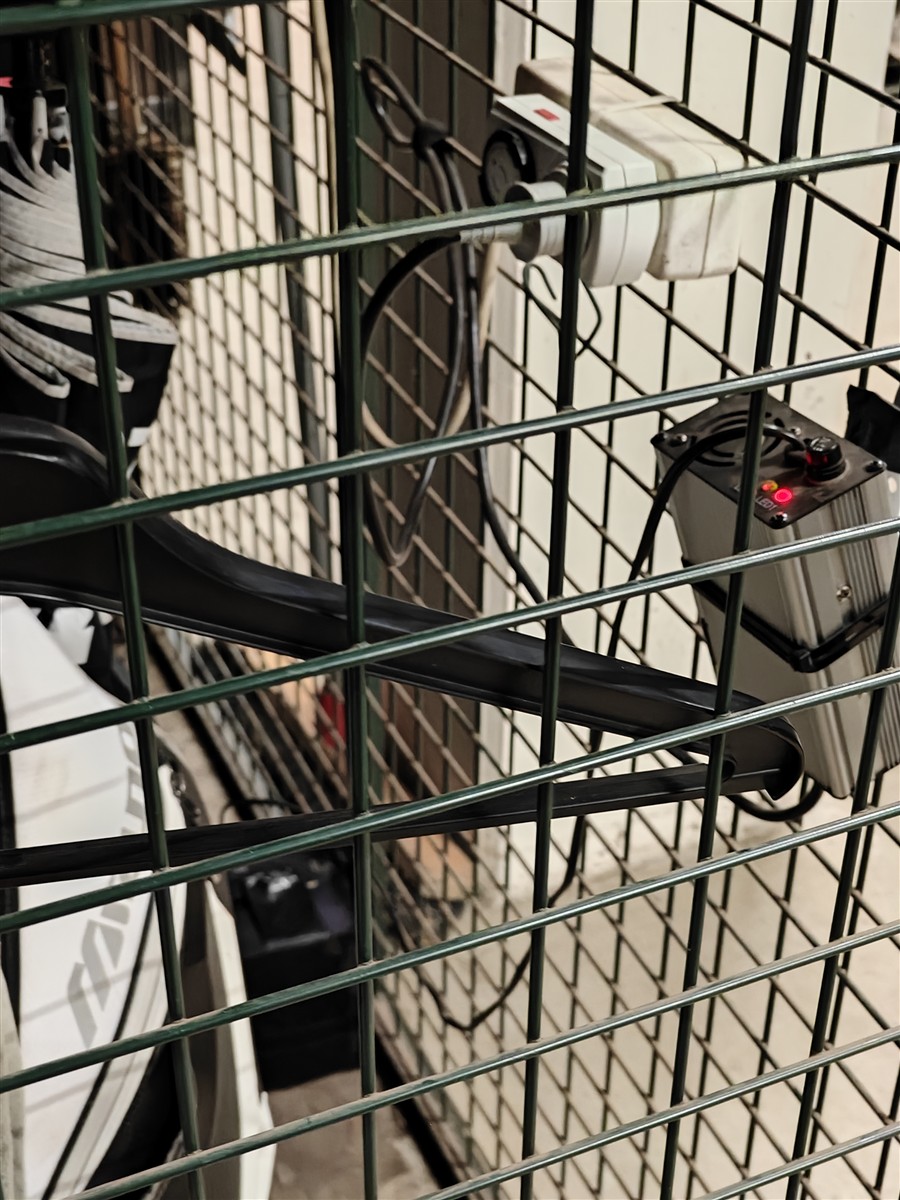 Stopcontacten en een acculader achter het gaas van een trolleylocker
