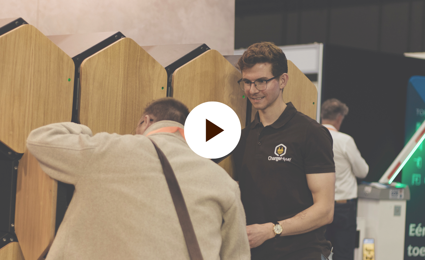 ChargeHyve-medewerker begeleidt een bezoeker op de Vakbeurs Facilitair & Gebouwbeheer 2026 bij het gebruik van een laadlocker voor e-bikeaccu&rsquo;s.